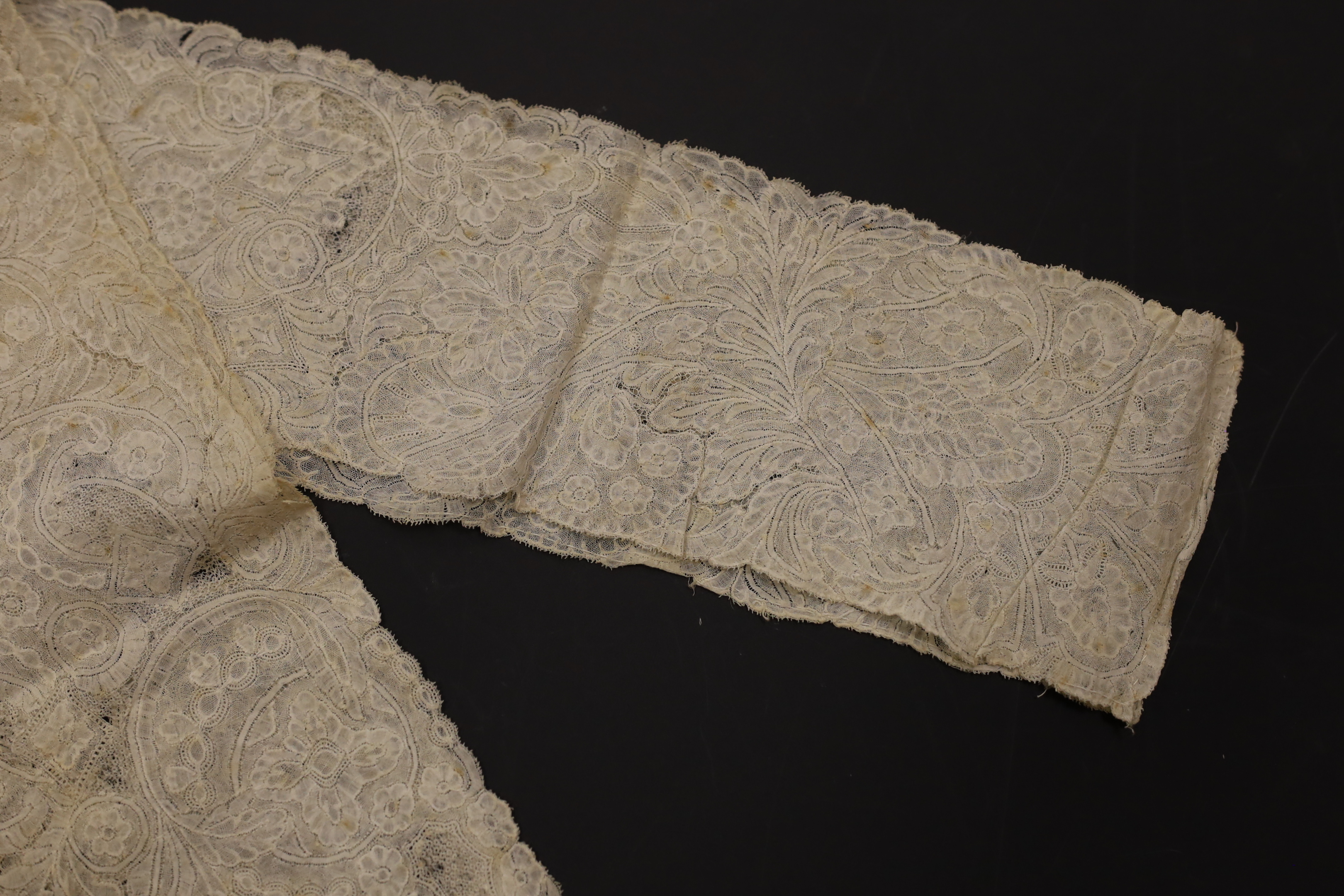 An early 18th century Hollie point insertion baby’s linen vest, three baby bonnets with Hollie point insertions and an early 18th century pair of Flemish bobbin lace lappets, a partly finished needlepoint length of lace,